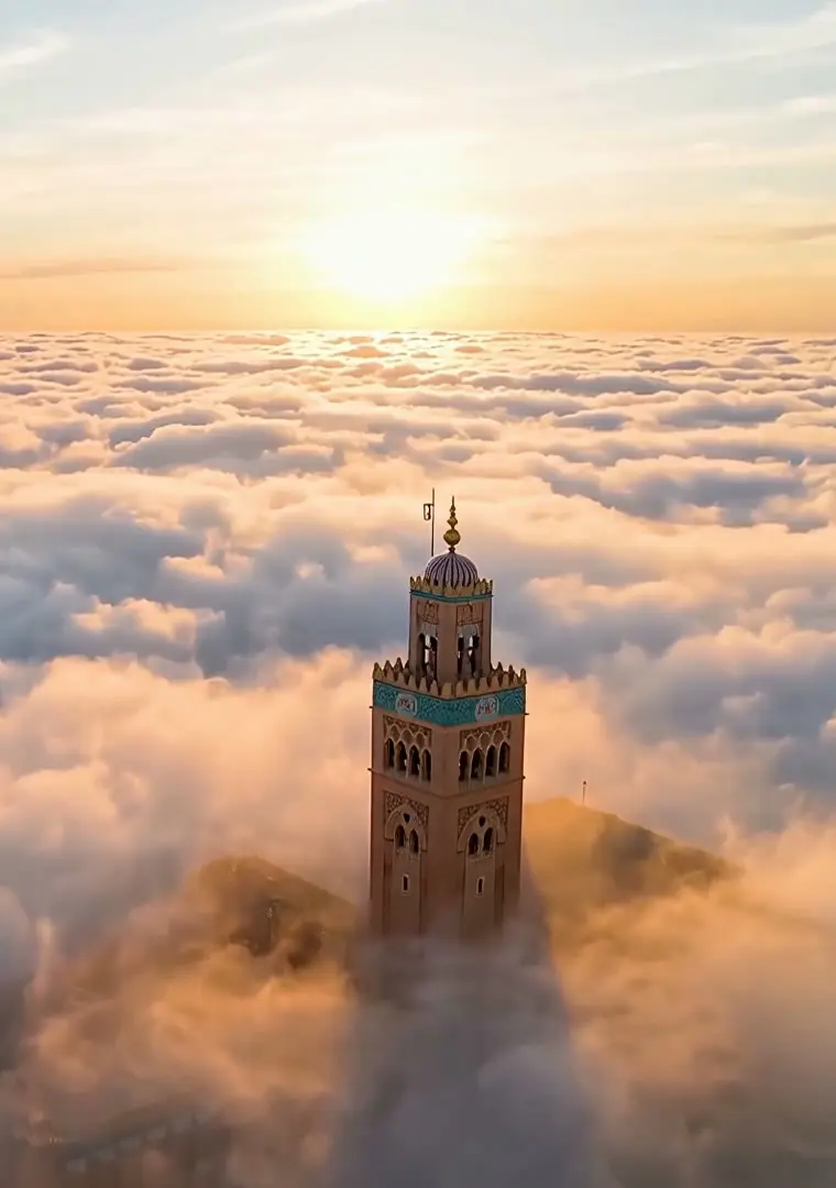 A Moroccan minaret rising above a sea of clouds in the light of the setting sun